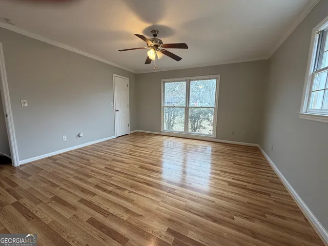 a view of an empty room with wooden floor and a window