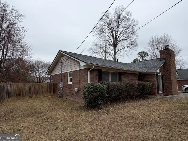 a view of a house with a yard and large trees