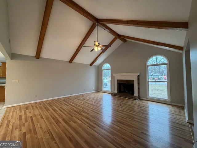 a view of an empty room with wooden floor fireplace and a window
