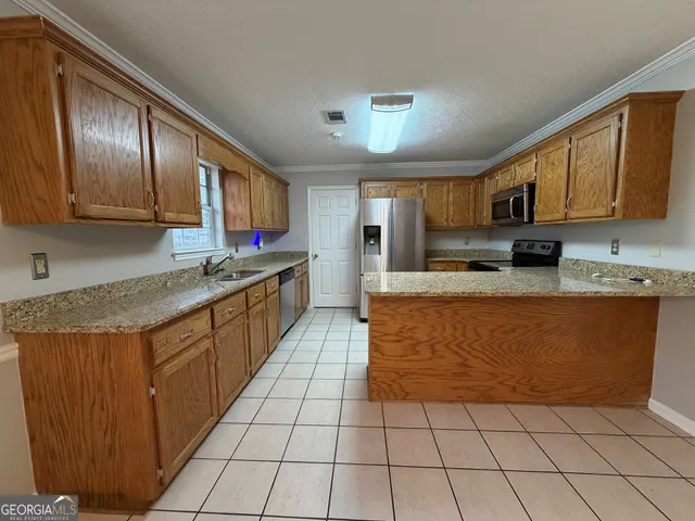 a large kitchen with stainless steel appliances granite countertop a stove a sink dishwasher a refrigerator and cabinets with wooden floor