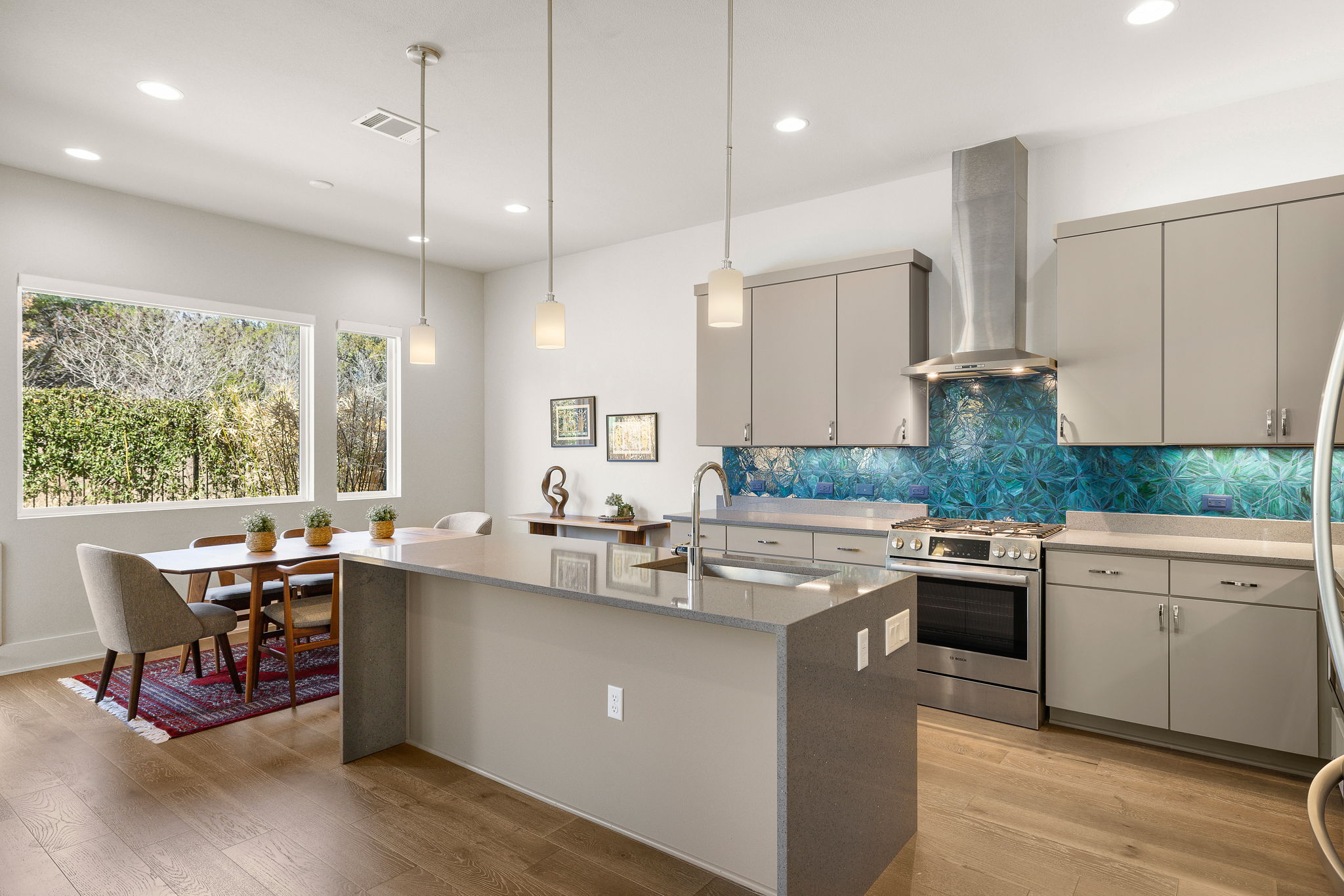 5214 Pink Poppy Pass Austin, TX 78735 - Photo 11 of 34 Kitchen with stainless steel range with gas stovetop, a kitchen island with sink, light stone counters, and light wood-style floors