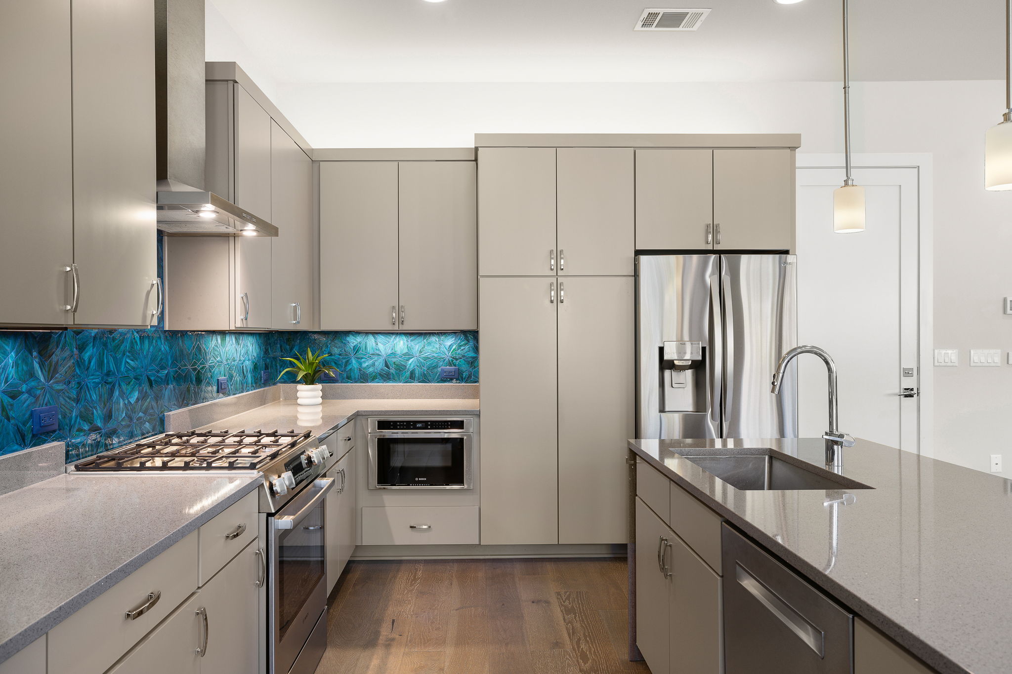 5214 Pink Poppy Pass Austin, TX 78735 - Photo 12 of 34 Kitchen with stainless steel appliances, dark stone countertops, hanging light fixtures, dark wood finished floors, and gray cabinets