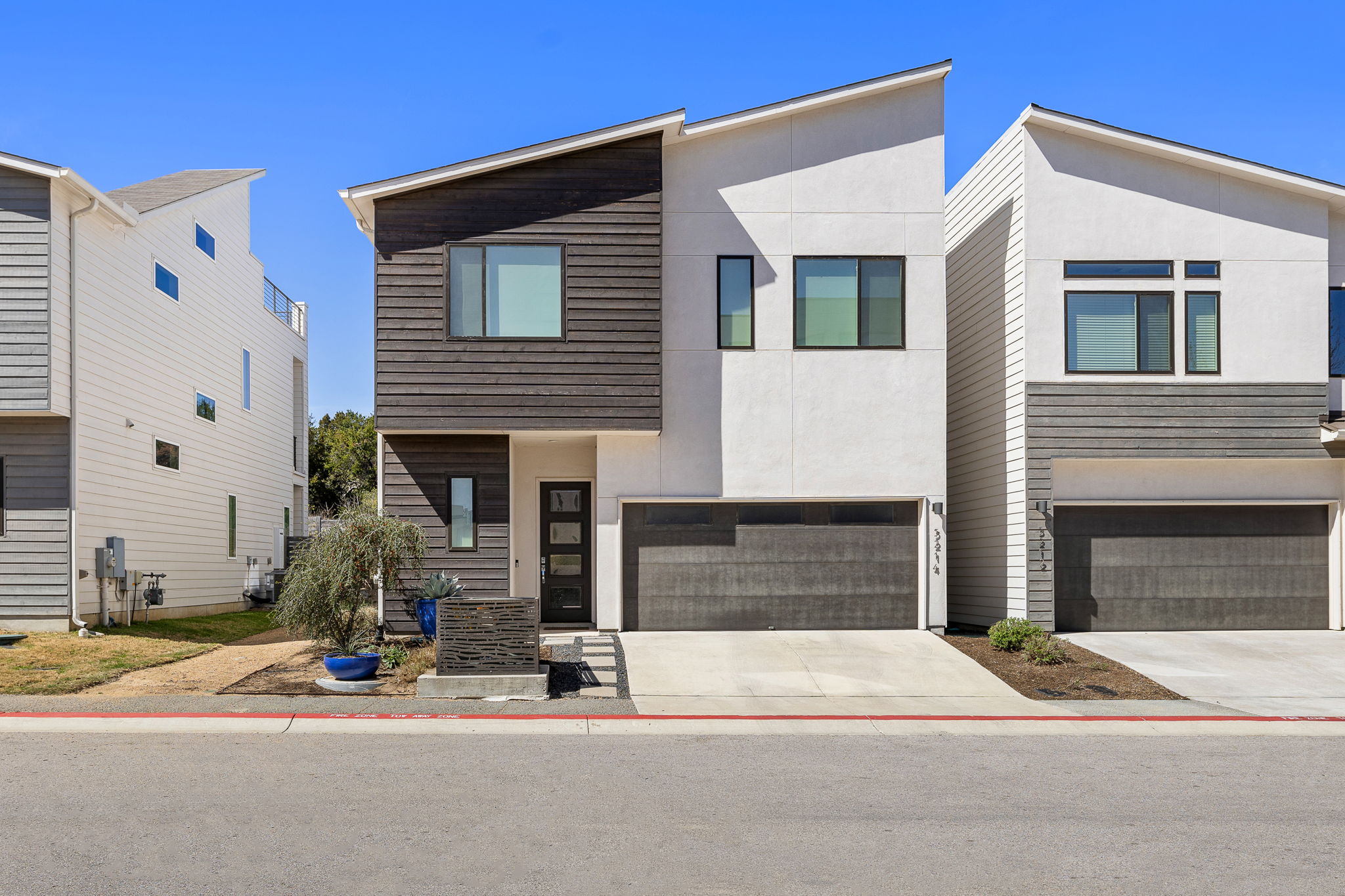 5214 Pink Poppy Pass Austin, TX 78735 - Photo 3 of 34 Modern home featuring stucco siding, an attached garage, and concrete driveway