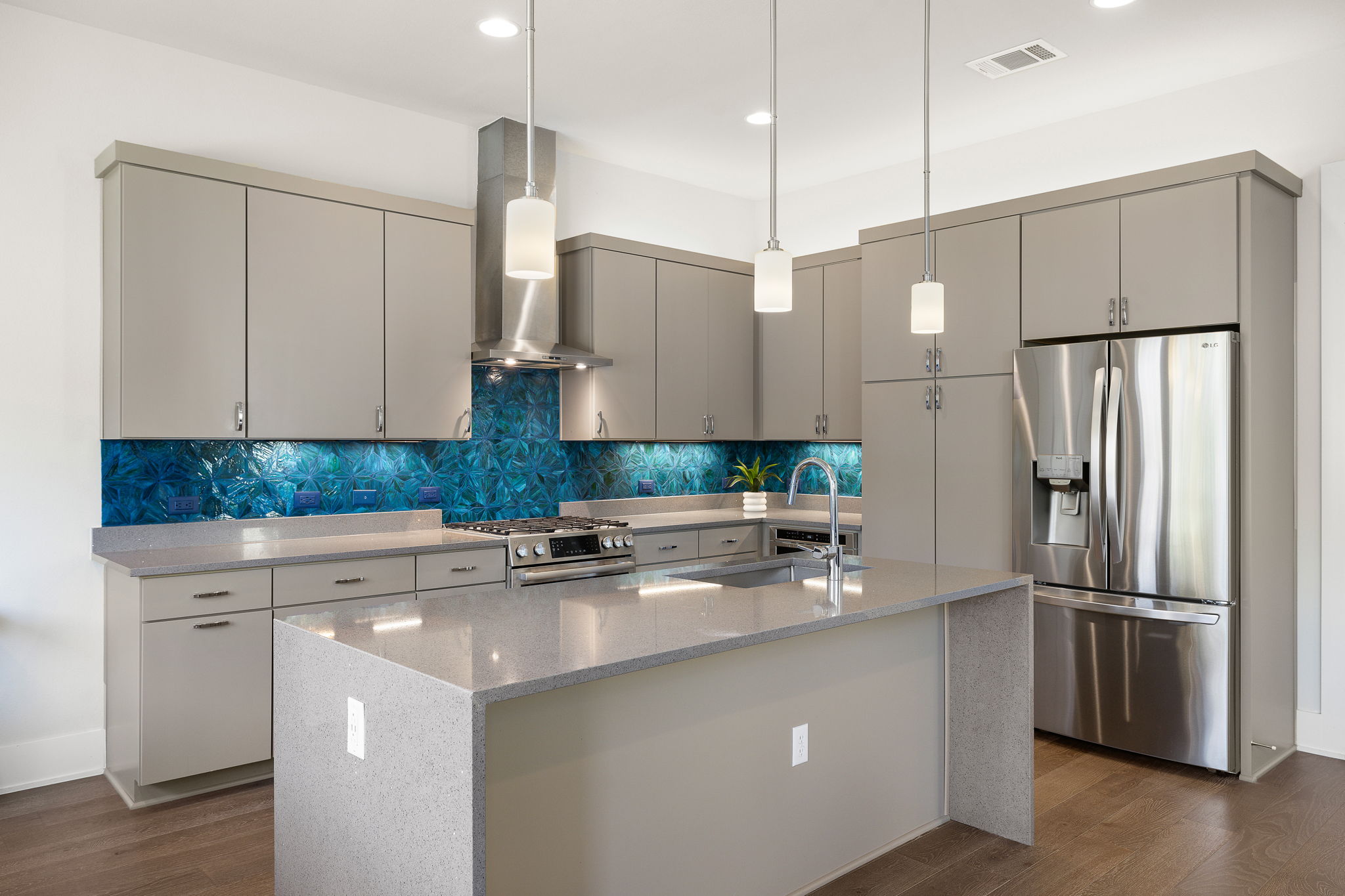 5214 Pink Poppy Pass Austin, TX 78735 - Photo 10 of 34 Kitchen featuring stainless steel appliances, light stone countertops, a center island with sink, hanging light fixtures, and gray cabinets