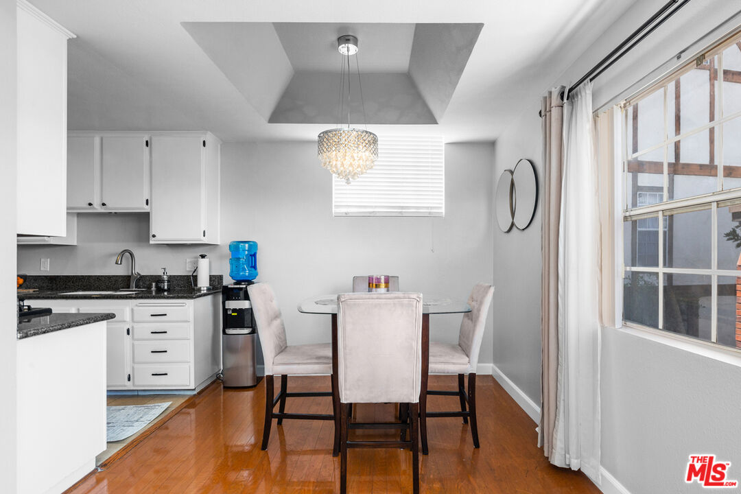 3800 Stocker Street, Unit 23 View Park, CA 90008 - Photo 6 of 33 a kitchen with stainless steel appliances granite countertop a stove top oven a sink a dining table and chairs with wooden floor