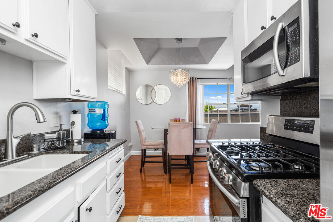 3800 Stocker Street, Unit 23 View Park, CA 90008 - Photo 10 of 33 a kitchen with stainless steel appliances granite countertop a stove a sink dishwasher and cabinets with wooden floor