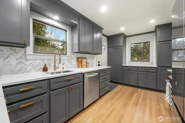 a kitchen with stainless steel appliances a sink cabinets and wooden floor