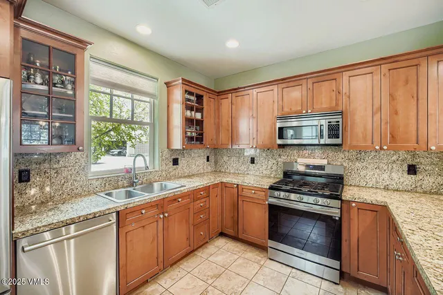 a kitchen with stainless steel appliances granite countertop a stove sink microwave and window