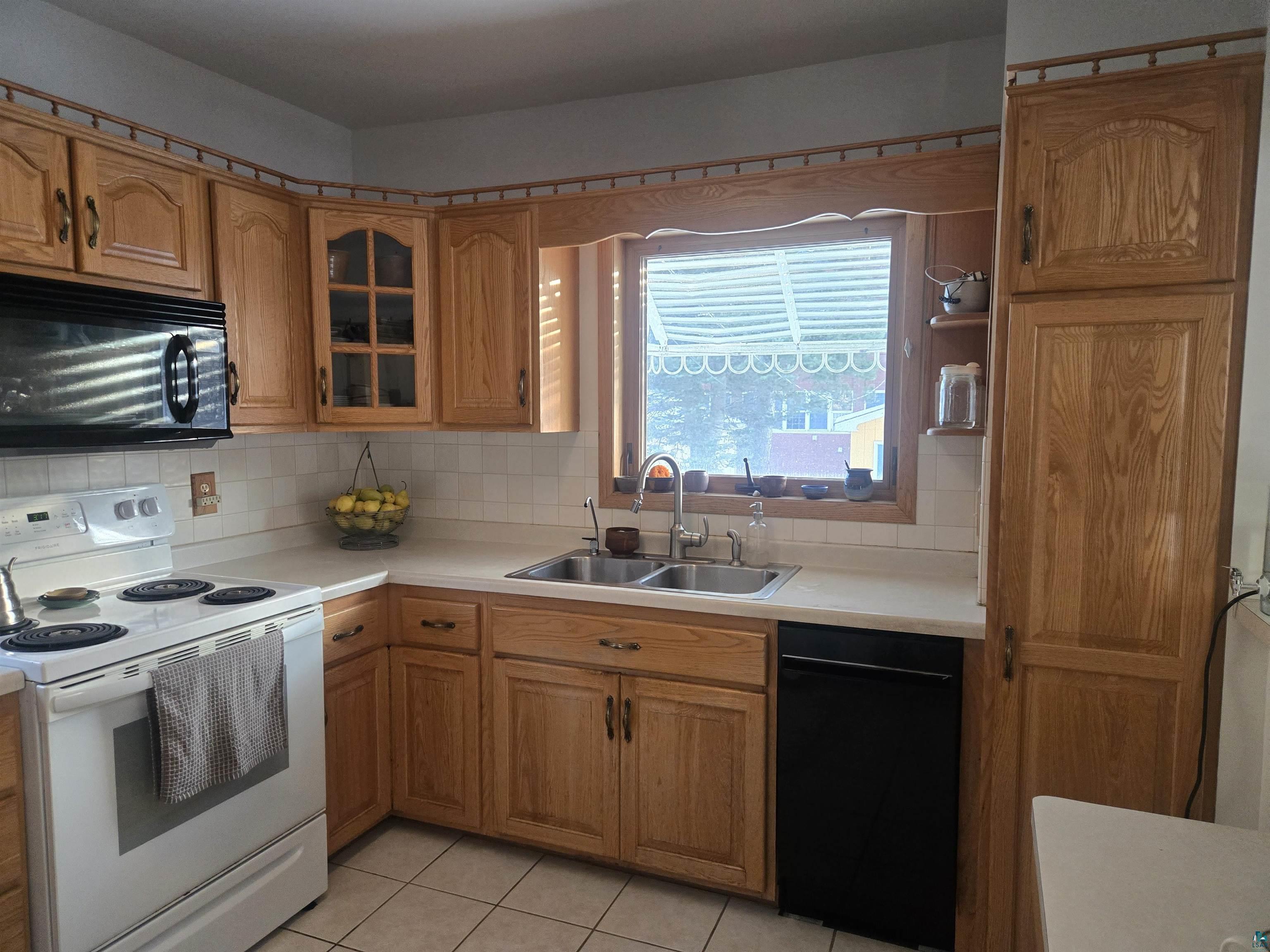 26 3rd Street Proctor, MN 55810 - Photo 26 of 26 Kitchen featuring black appliances, brown cabinetry, light countertops, and glass insert cabinets