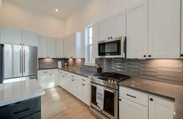 a kitchen with granite countertop white cabinets stainless steel appliances and a sink