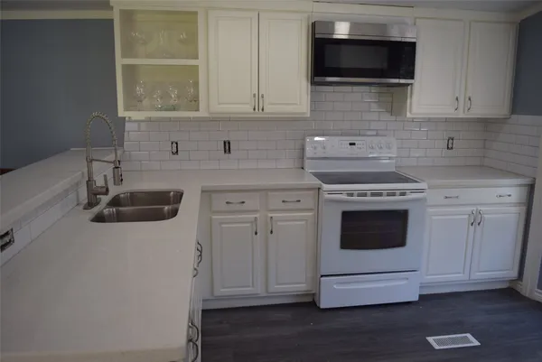 a kitchen with stainless steel appliances granite countertop white cabinets a microwave oven a sink and dishwasher with wooden floor
