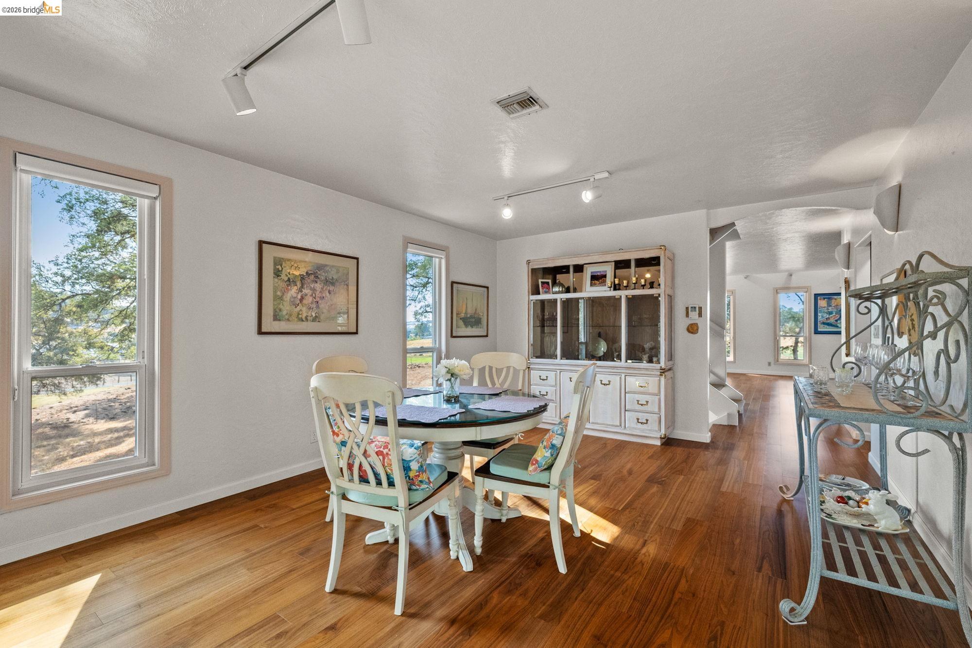 10566 Thistle Down Road Jamestown, CA 95327 - Photo 14 of 53 Dining space featuring track lighting, arched walkways, hardwood / wood-style flooring, and a textured ceiling
