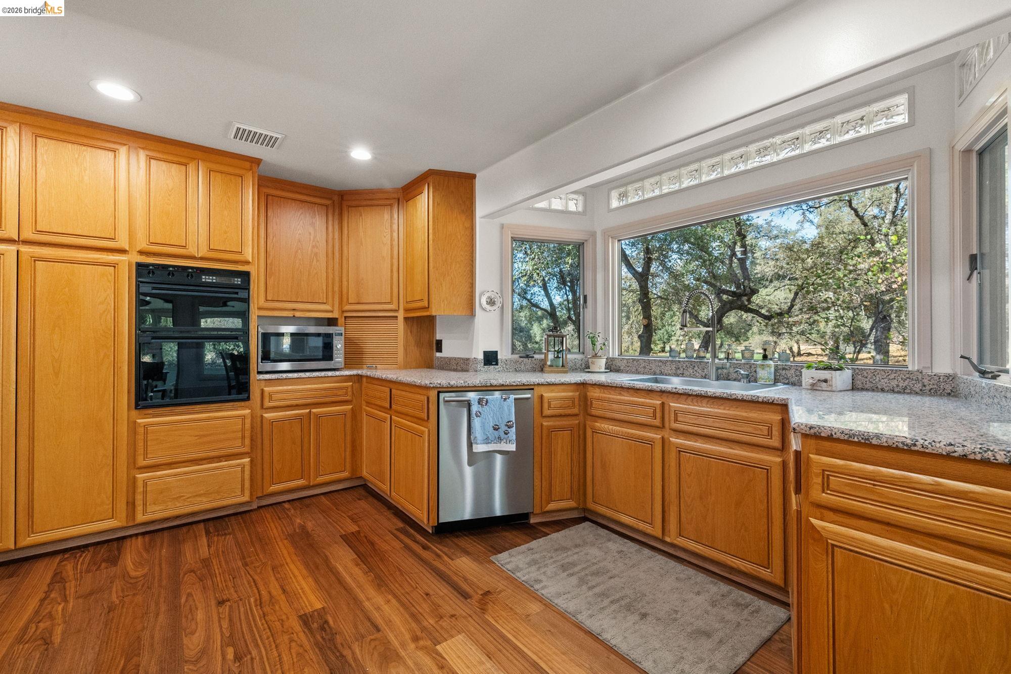 10566 Thistle Down Road Jamestown, CA 95327 - Photo 17 of 53 Kitchen featuring stainless steel appliances, dark wood-style flooring, light stone counters, wood finish cabinetry, and recessed lighting