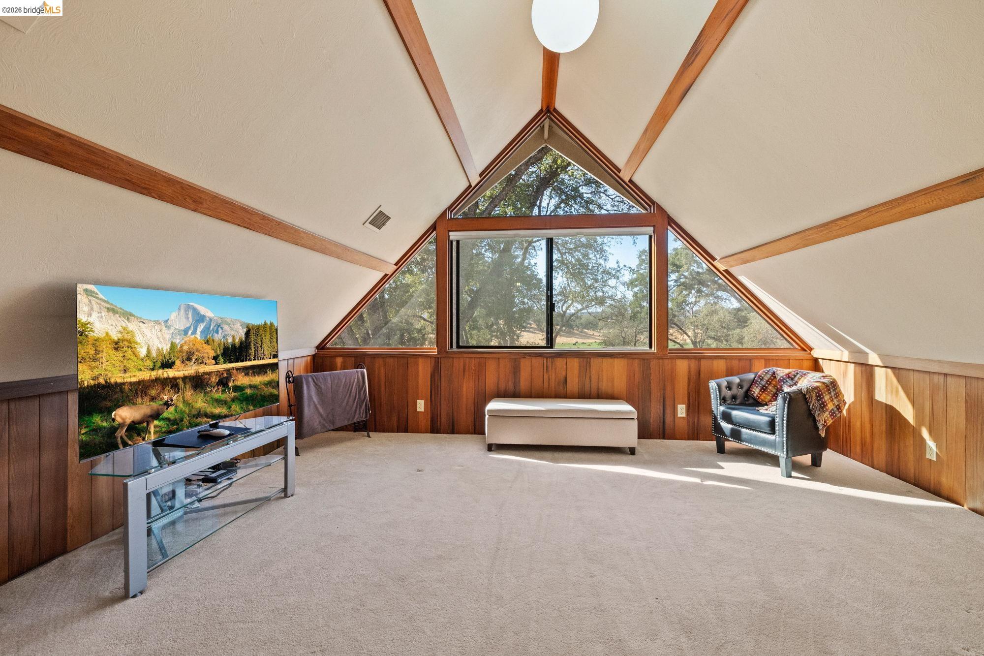 10566 Thistle Down Road Jamestown, CA 95327 - Photo 24 of 53 Living area featuring wood walls, carpet, a wainscoted wall, and beam ceiling