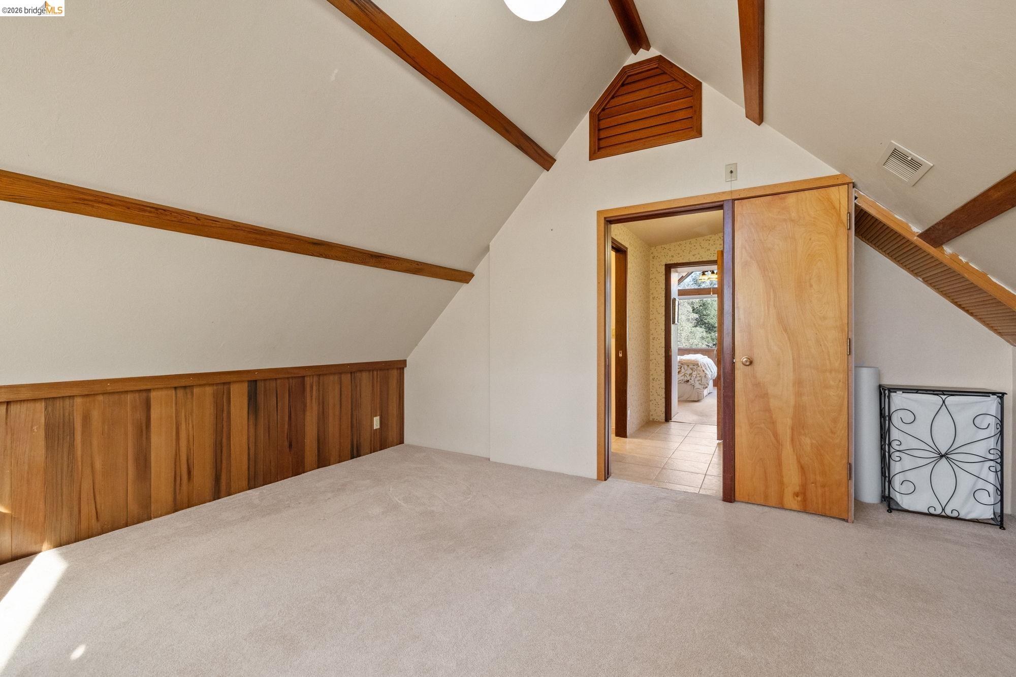 10566 Thistle Down Road Jamestown, CA 95327 - Photo 25 of 53 Additional living space with beam ceiling, light colored carpet, and wood walls