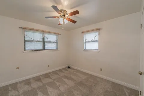 an empty room with a window and a ceiling fan