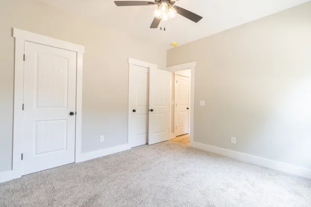 an empty room with windows and fan