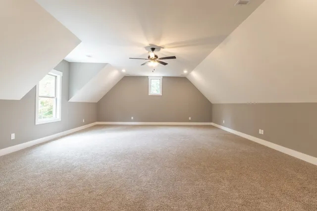 an empty room with windows and chandelier fan