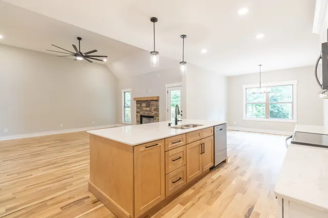 a kitchen with a stove a sink a window and wooden floor
