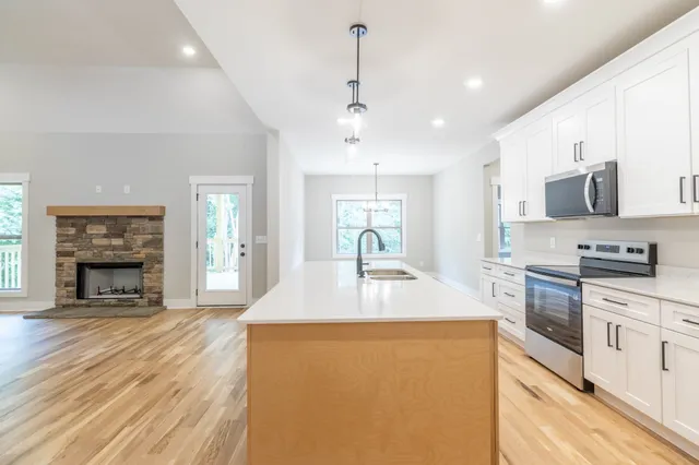 a kitchen with kitchen island a stove a sink a refrigerator dining table and chairs