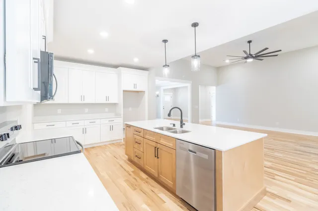 a kitchen with a sink a stove a refrigerator and white cabinets