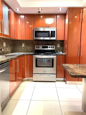 a kitchen with stainless steel appliances kitchen island granite countertop a stove a sink and a microwave