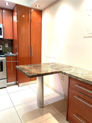 a view of a room with kitchen island granite countertop lots of counter top space and cabinets
