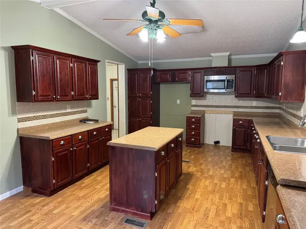 a kitchen with kitchen island granite countertop a sink dishwasher stove and cabinets