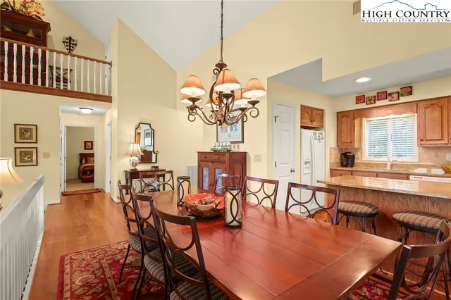 a dining room with wooden floor a chandelier a glass table and chairs