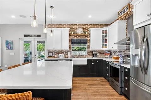 a kitchen with a stove a sink and a living room view