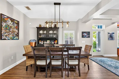 a dining room with wooden floor a chandelier a wooden table and chairs