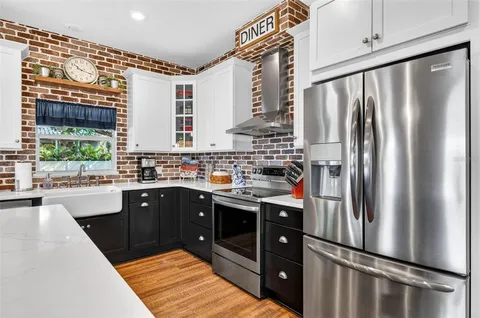 a large kitchen with stainless steel appliances a large counter top a stove a chimney a sink and a refrigerator