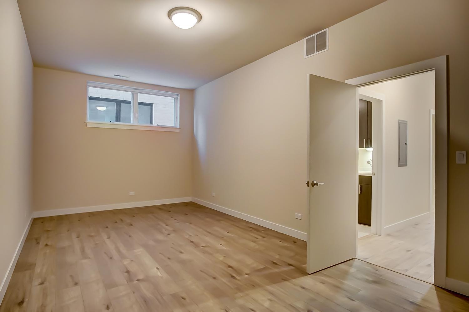 2532 West Addison Street, Unit 1W Chicago, IL 60618 - Photo 19 of 24 a view of an empty room with wooden floor and a bathroom