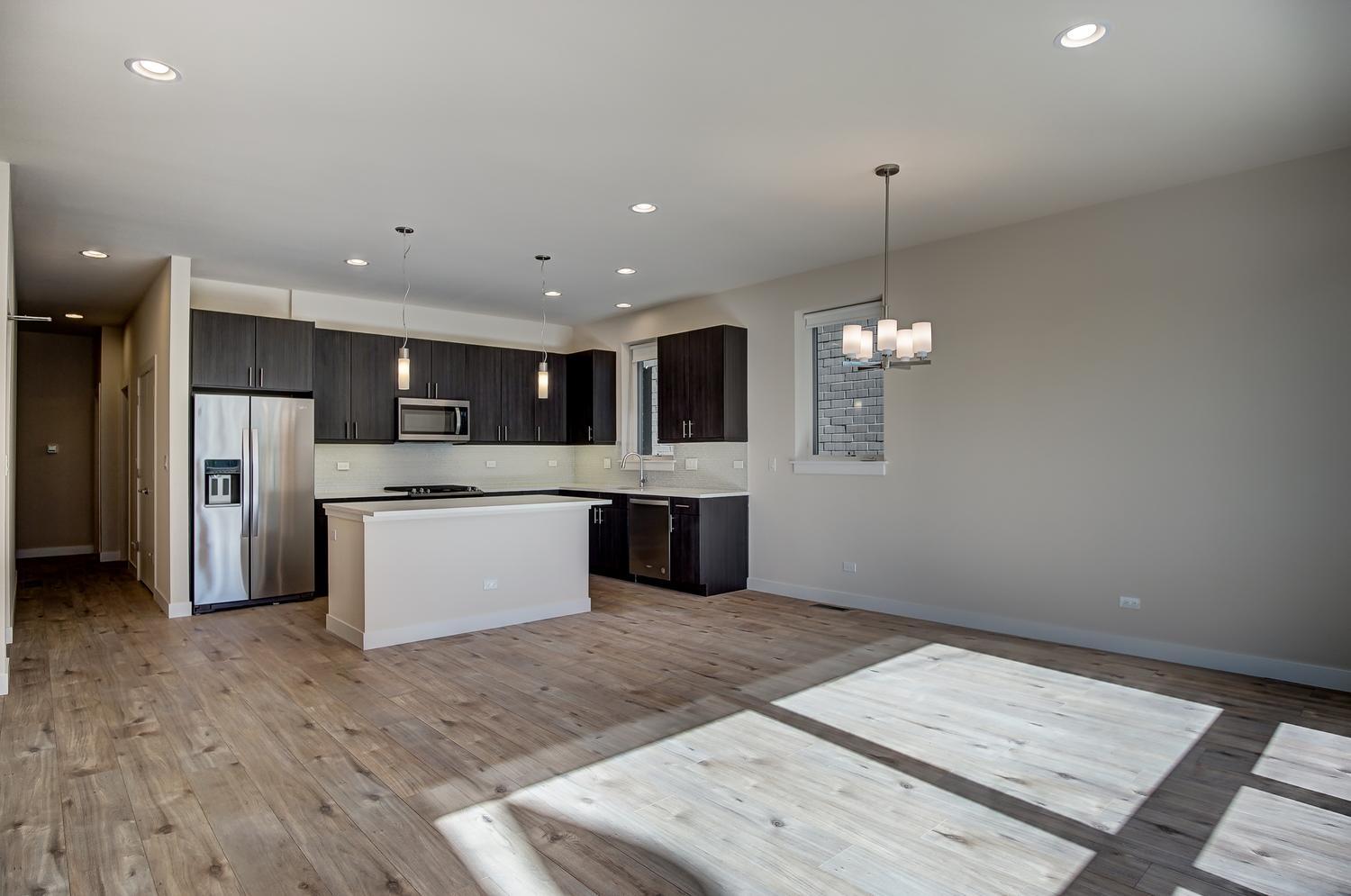 2532 West Addison Street, Unit 1W Chicago, IL 60618 - Photo 4 of 24 a large kitchen with a refrigerator a sink dishwasher a oven and a dining table with wooden floor