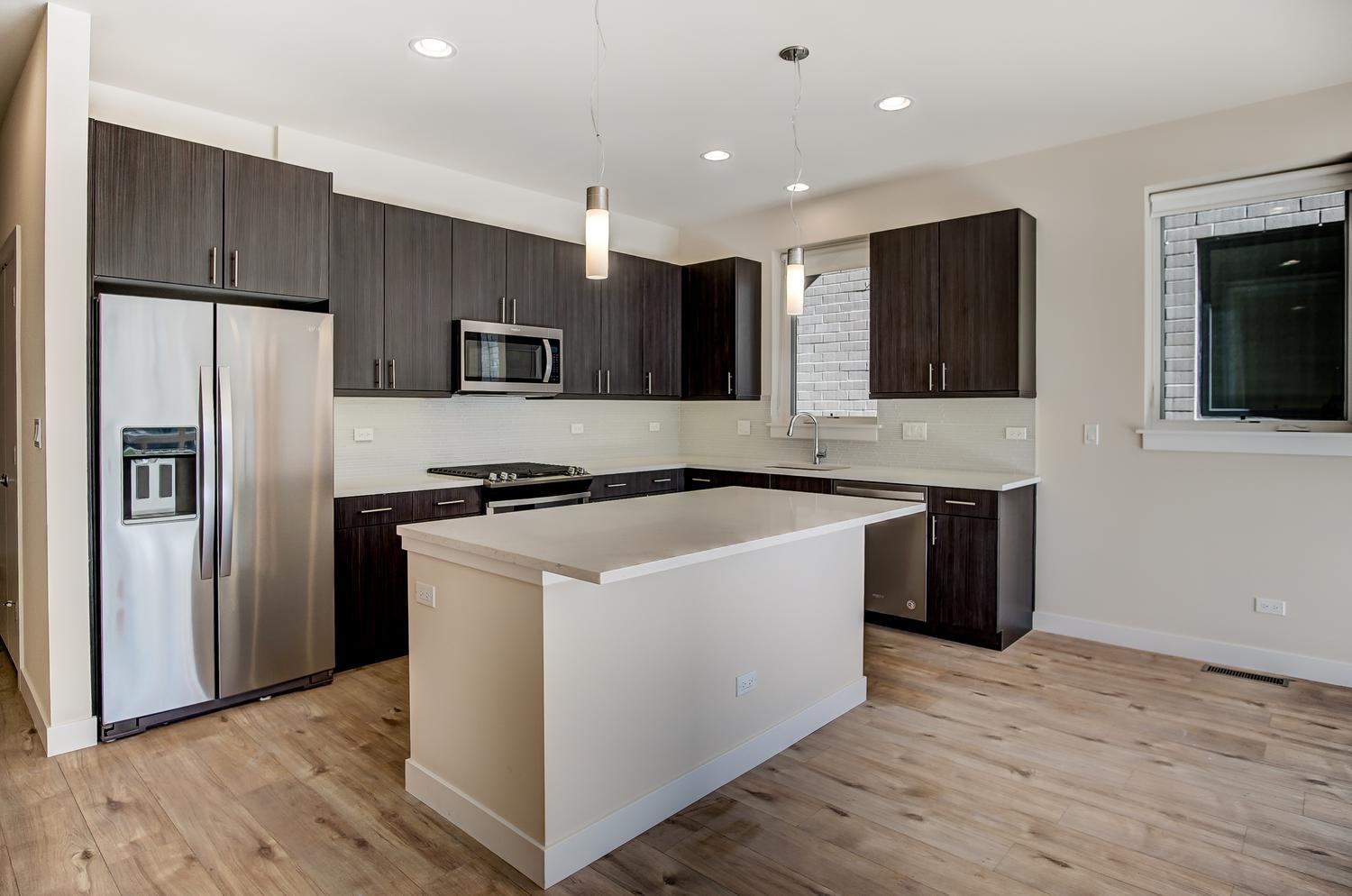 2532 West Addison Street, Unit 1W Chicago, IL 60618 - Photo 5 of 24 a large kitchen with stainless steel appliances kitchen island granite countertop a refrigerator and a stove top oven