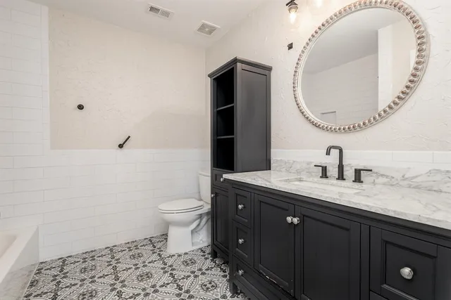 a bathroom with a granite countertop toilet sink and mirror