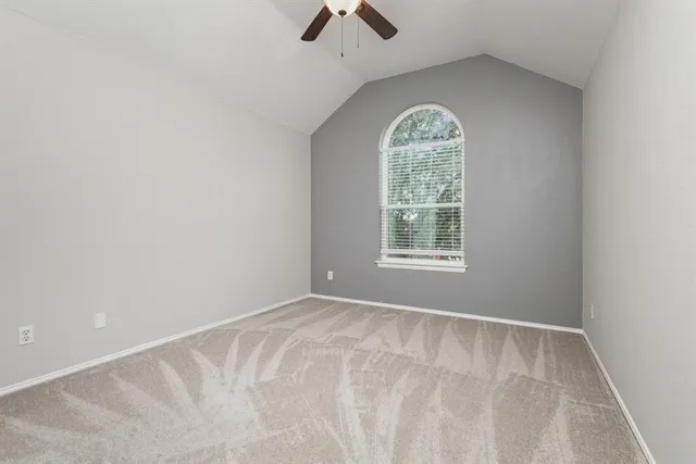 an empty room with a window and ceiling fan