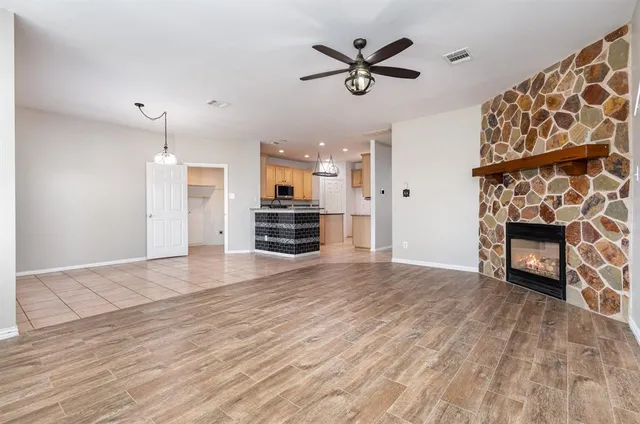 an empty room with wooden floor a fireplace and windows