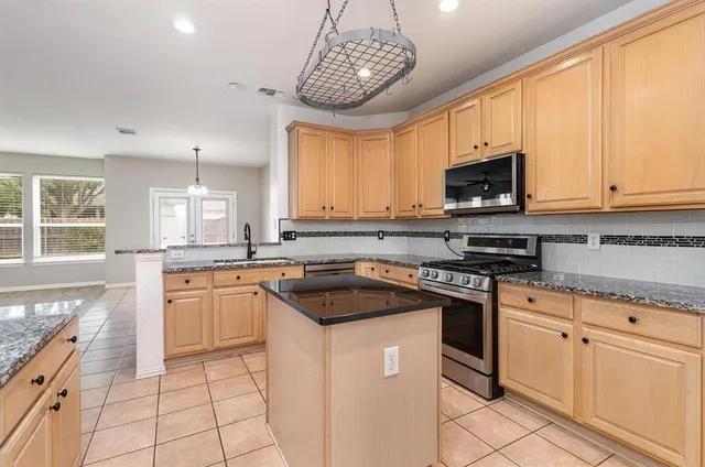 a kitchen with stainless steel appliances granite countertop a stove a sink and a microwave