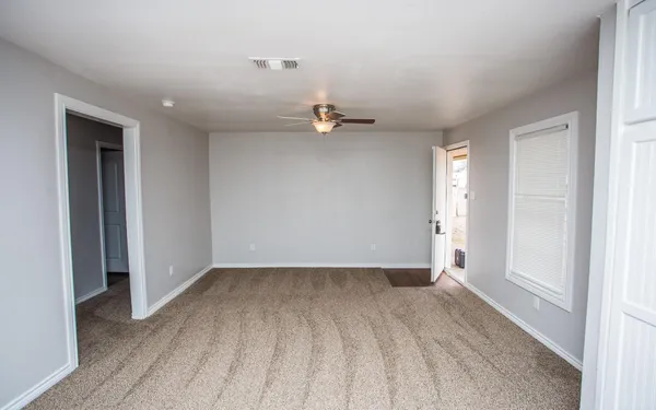 an empty room with a window and a ceiling fan
