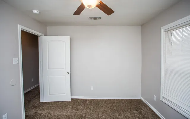 an empty room with a window and a ceiling fan