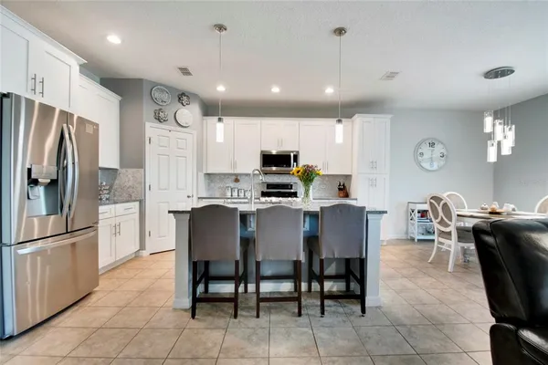a kitchen with stainless steel appliances granite countertop a refrigerator a stove a sink a dining table and chairs