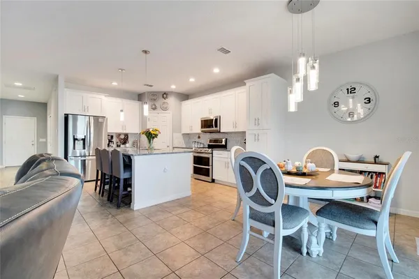 a dining room filled chandelier and kitchen view