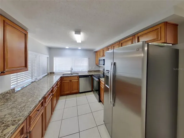 a kitchen with stainless steel appliances granite countertop a refrigerator a sink and a stove