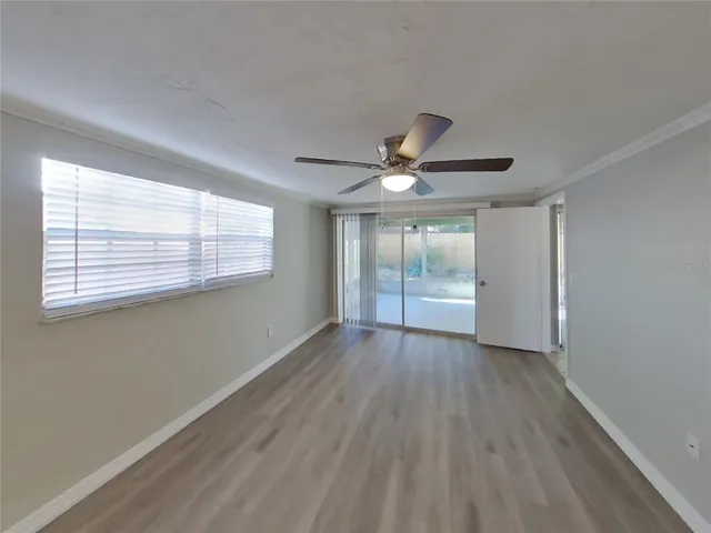a view of an empty room with wooden floor and a window