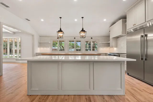 a kitchen with stainless steel appliances granite countertop a sink a refrigerator and wooden floors