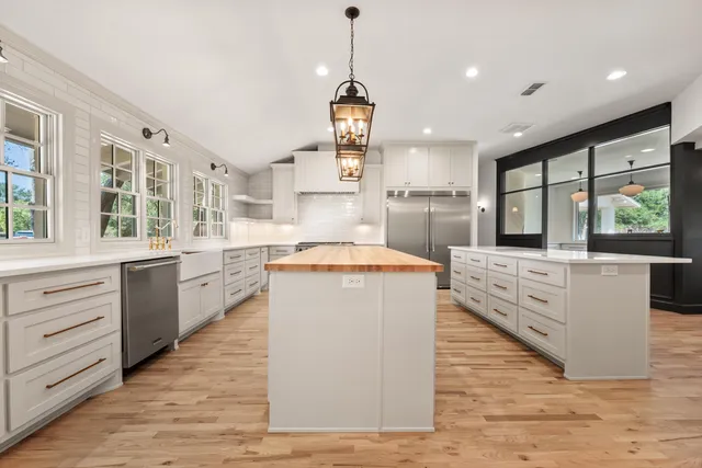 a large kitchen with kitchen island a large counter top space a sink stainless steel appliances and windows