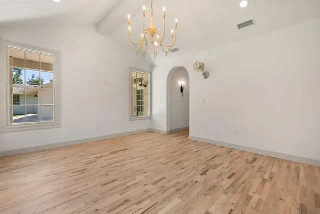 a view of a livingroom with a chandelier fan windows and wooden floor