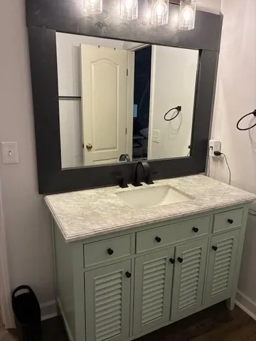 a bathroom with a granite countertop sink a mirror and a bathtub