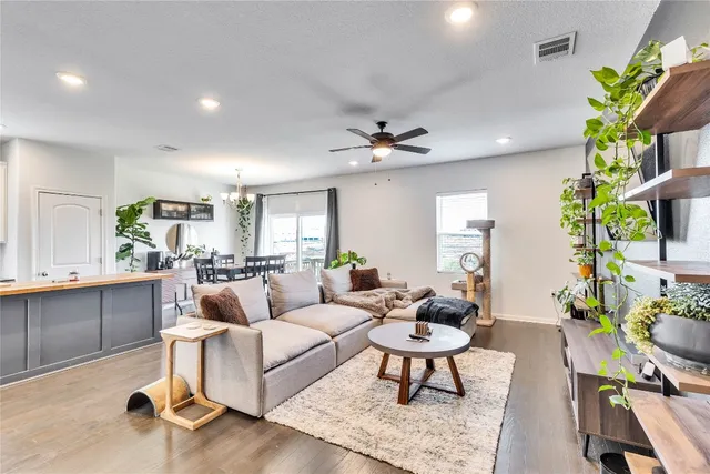 a living room with furniture a chandelier and a dining table with wooden floor